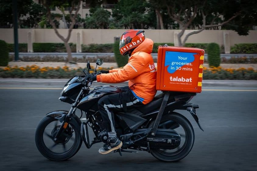 Motociclista entregando comida, repartidor de Talabat en una carretera de Dubái.