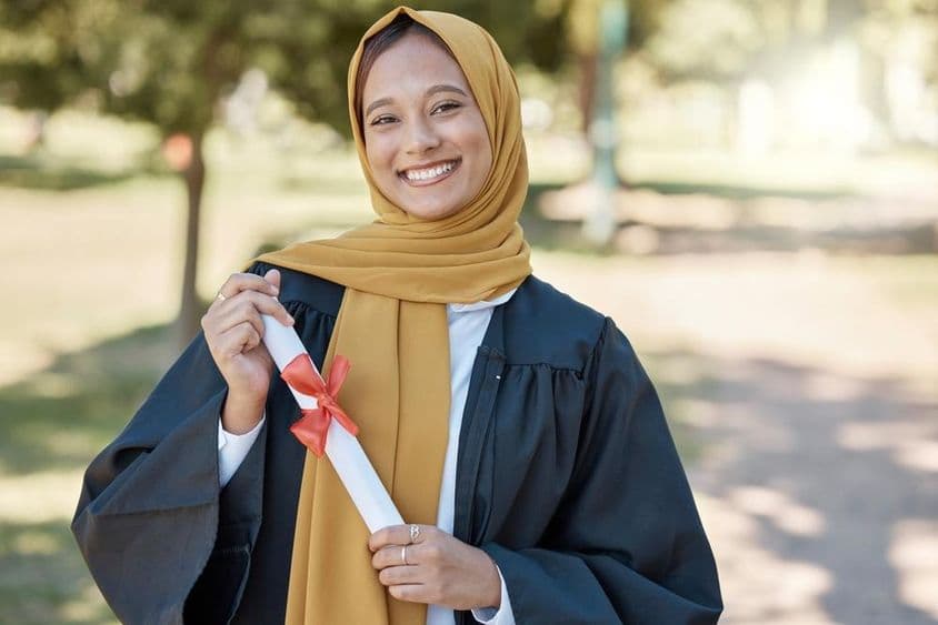 Estudiante islámico con un diploma en una universidad al aire libre.