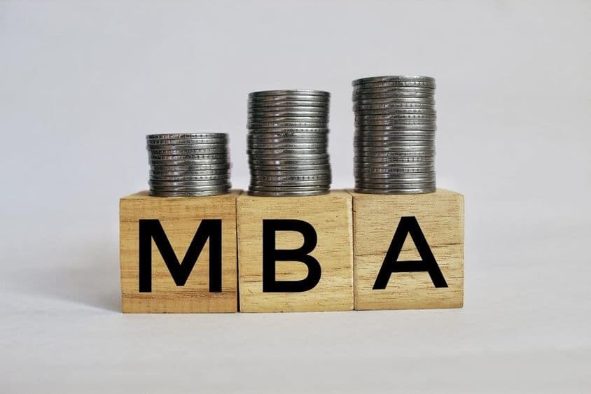 MBA Maestría en Administración de Empresas escrito en cubos apilados sobre monedas.