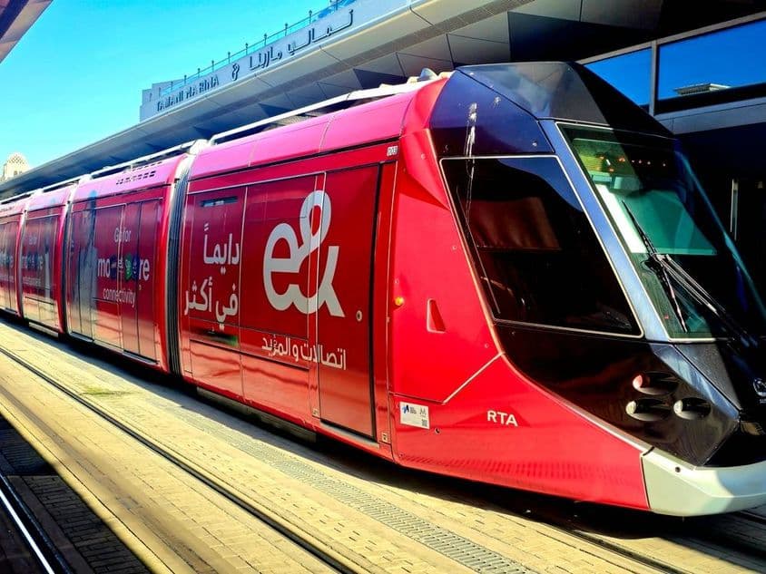 Un tranvía rojo con anuncios de Etisalat.