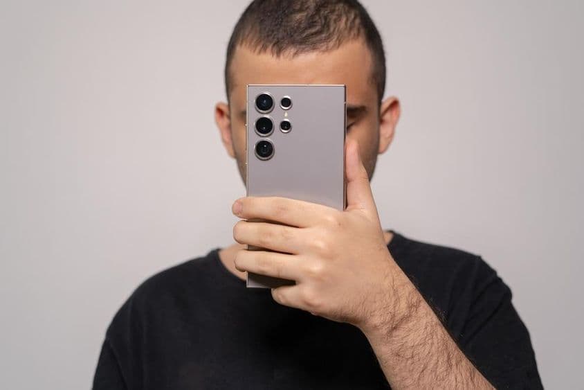 Hombre sosteniendo un smartphone Samsung S24 Ultra, resaltando el diseño elegante.