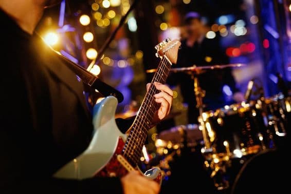 Un guitarrista tocando un acorde en el diapasón durante la actuación de una banda.