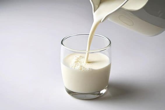 Vertiendo leche en un vaso pequeño.