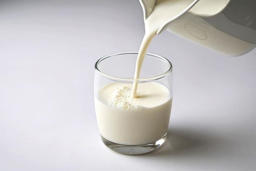 Vertiendo leche en un vaso pequeño.