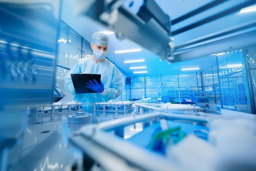 Trabajador farmacéutico operando una línea de producción en la industria farmacéutica.