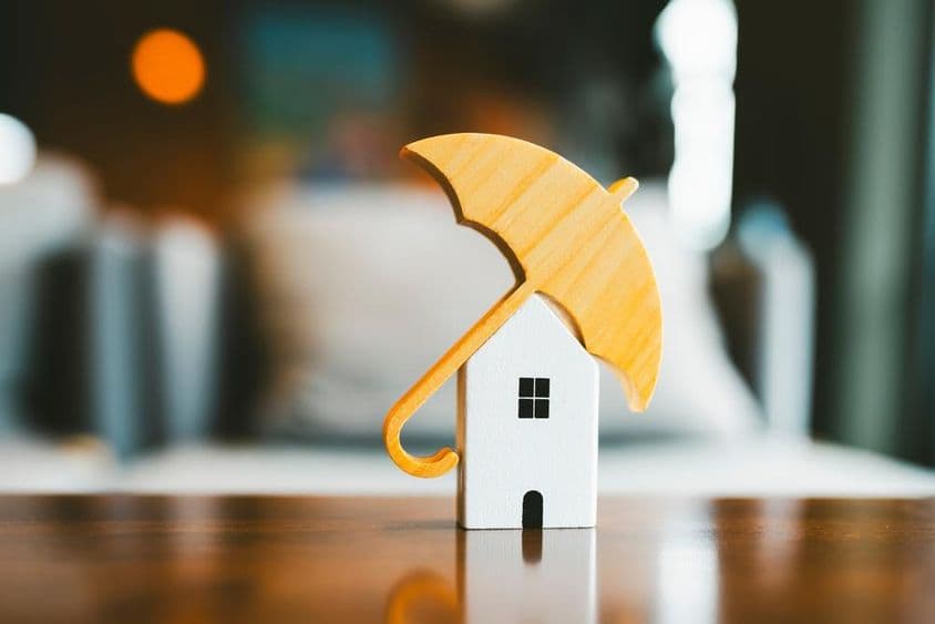 Modelo de paraguas sobre una casa de madera, seguro de hogar.