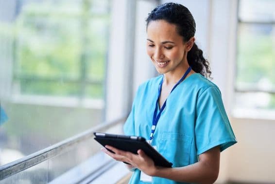 Enfermera sonriente con una tableta digital en una instalación médica moderna.