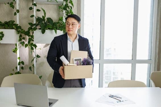 Un hombre es despedido de su lugar de trabajo, empacando sus pertenencias personales en una caja de cartón.