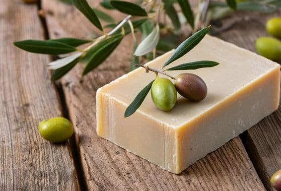 Un jabón de aceite de oliva hecho a mano descansa sobre una mesa de madera.