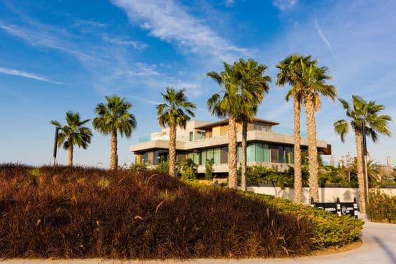 Dubái, villa rodeada de palmeras contra un atardecer nublado.