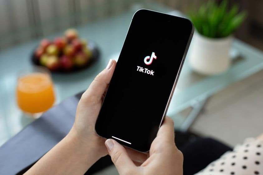 Apple iPhone 15 Pro Max en la mano de una mujer, video de TikTok en pantalla.
