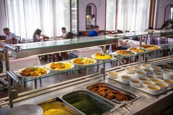Estudiantes siendo servidos durante el almuerzo escolar.