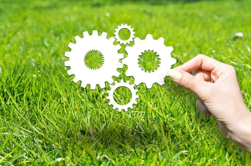 Concepto con ruedas y engranajes sobre césped verde.