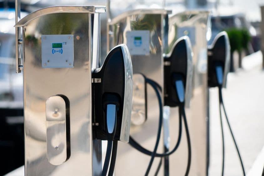 Estación de carga para coche eléctrico en una marina de lujo junto al mar.