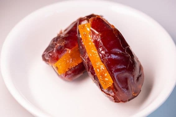 Dos increíbles dátiles frescos de Dubái con piezas de naranja azucaradas.
