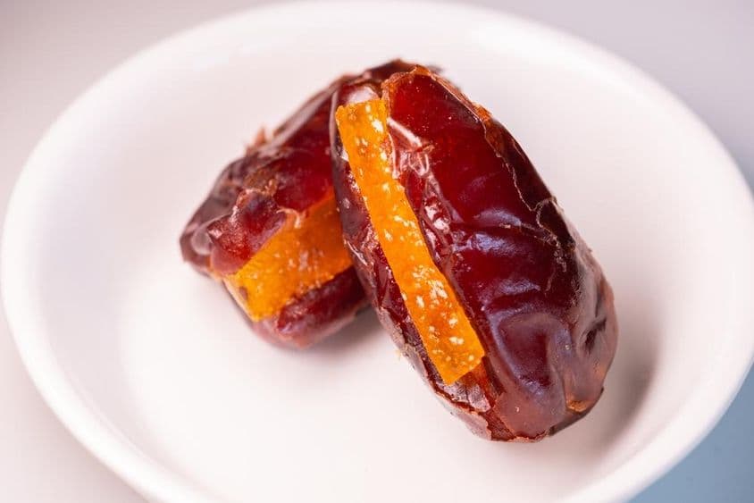 Dos increíbles dátiles frescos de Dubái con piezas de naranja azucaradas.
