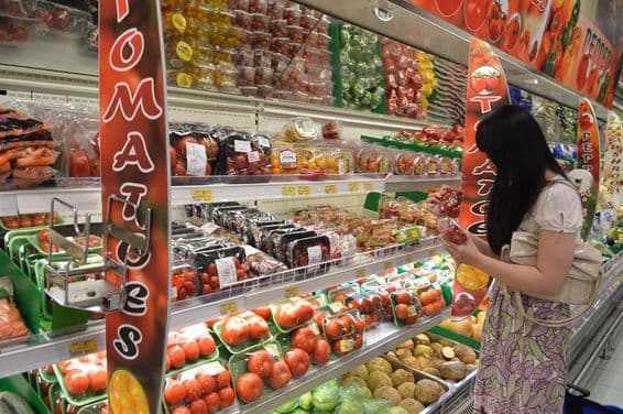 Compradora seleccionando fruta fresca en supermercado Lulu.