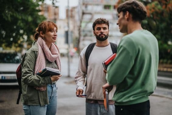 Grupo de estudiantes discutiendo al aire libre con libros en mano.