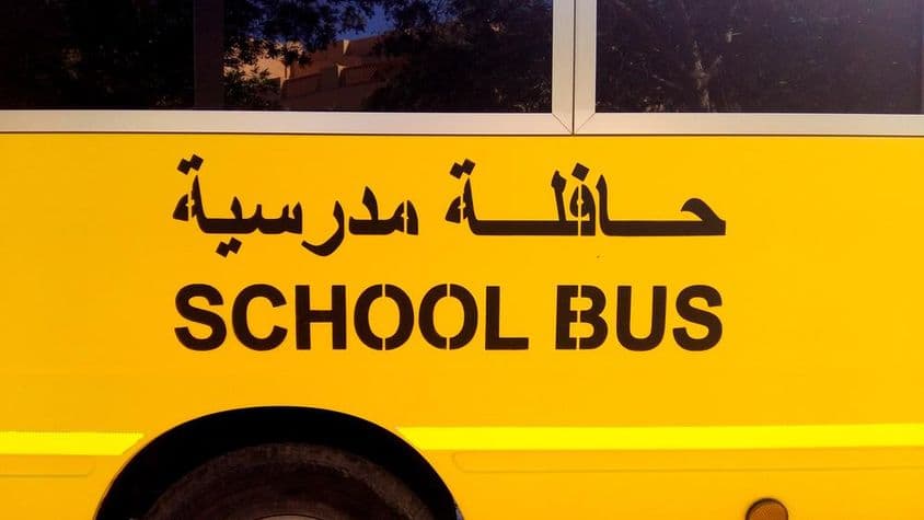 Autobús escolar de Dubái con texto en árabe.