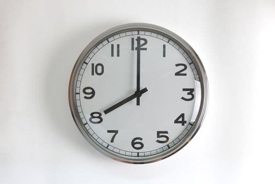 Reloj de pared redondo de acero inoxidable con cara blanca.