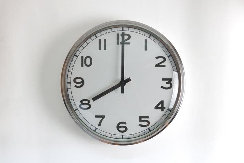 Reloj de pared redondo de acero inoxidable con cara blanca.