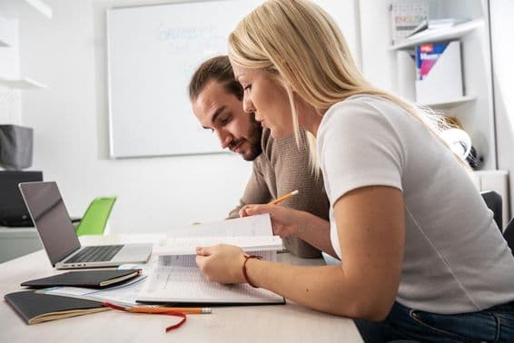 Dos estudiantes leyendo material del curso en un cuaderno.