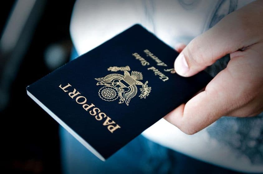 Hombre sosteniendo un pasaporte azul.