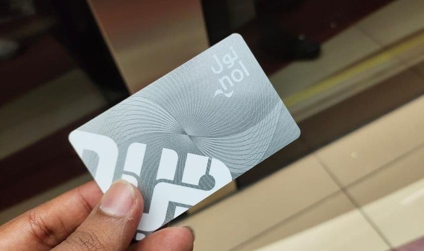 Viajero en Dubái sosteniendo una tarjeta Nol de metro como pase de entrada.