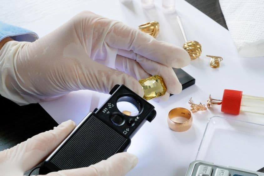 Probando joyería de oro antigua con reactivos y piedra de toque.