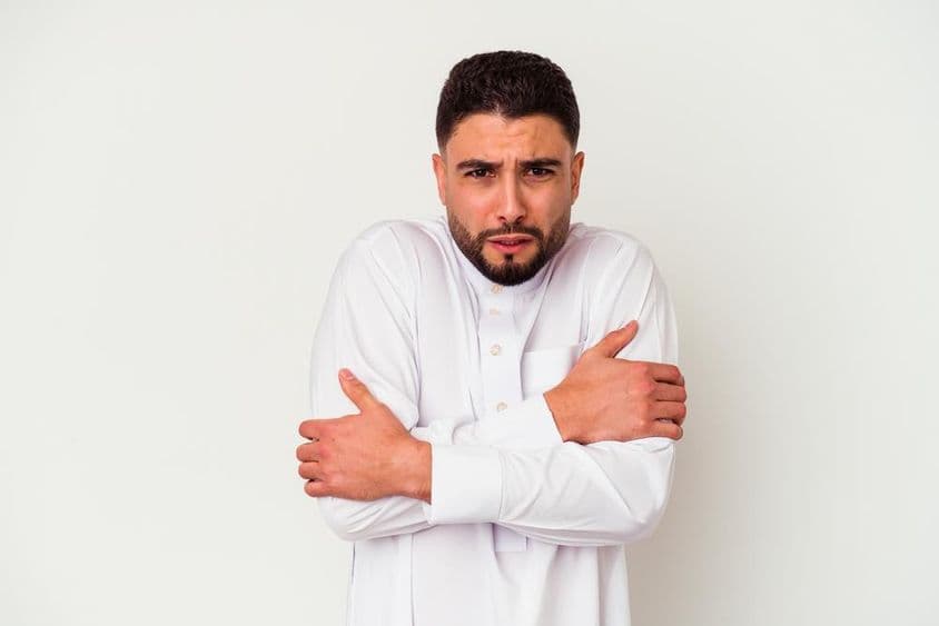 Joven árabe en atuendo tradicional temblando de frío.