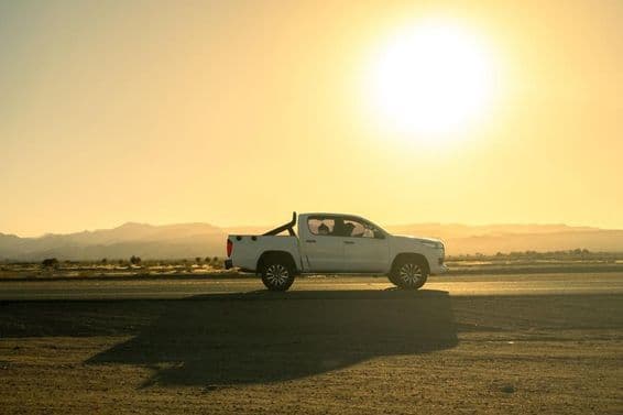 Vehículo pickup blanco en un viaje campestre, día soleado al atardecer.