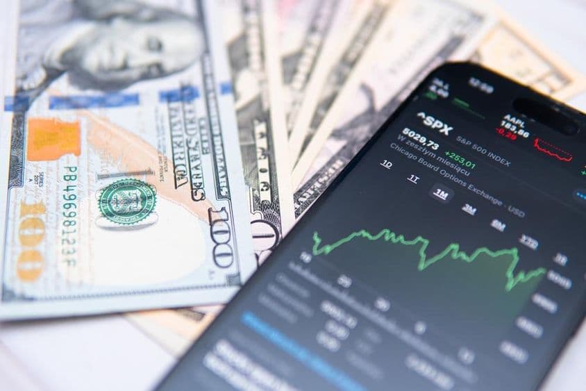 El índice S&P500 en pantalla de smartphone, con fondo de dólares estadounidenses.
