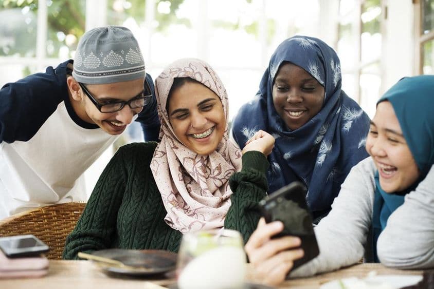 Grupo de estudiantes mirando una lección en un teléfono móvil.