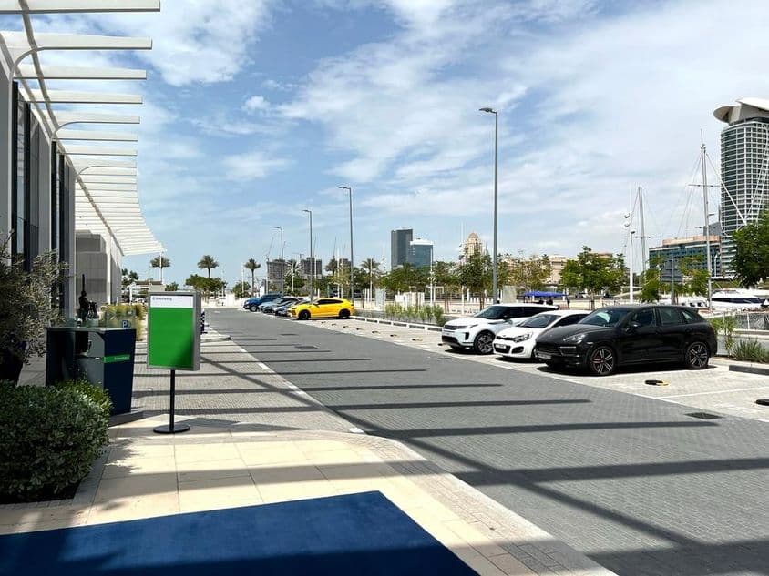 Aparcamiento en Dubái con el horizonte de la ciudad al fondo en un día de verano.