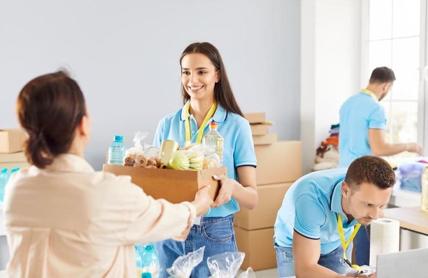 Voluntario joven entregando caja de donación de alimentos a los necesitados en una fundación caritativa.