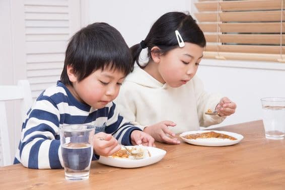 Niño come arroz al curry en casa.