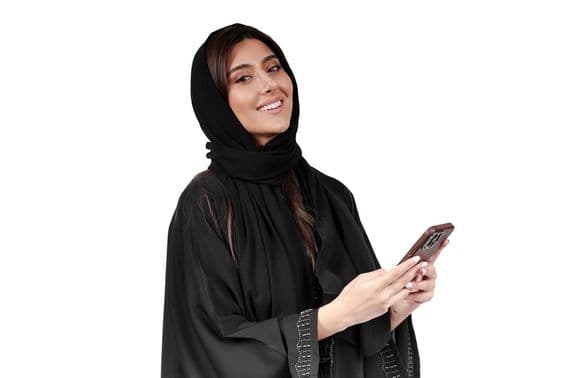 Empresaria emiratí en abaya árabe trabajando en un teléfono móvil.