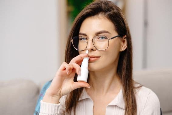Joven utilizando un spray nasal para facilitar la respiración.