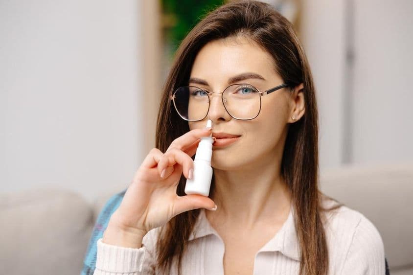 Joven utilizando un spray nasal para facilitar la respiración.