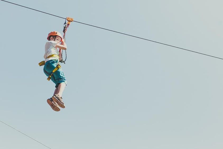 Niño escalando en un parque de aventuras en un soleado día de verano.