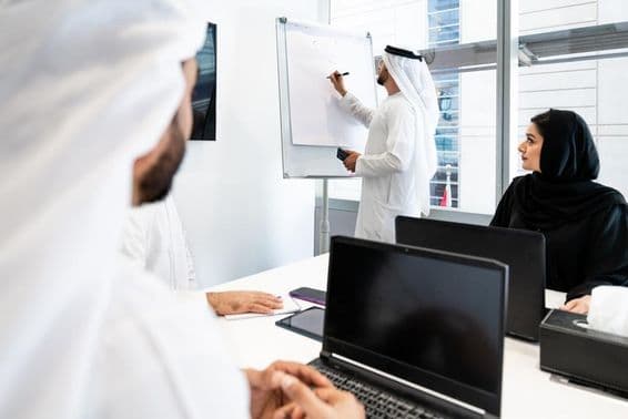 Un grupo de empresarios en atuendo tradicional emiratí teniendo una reunión en una oficina en Dubái.