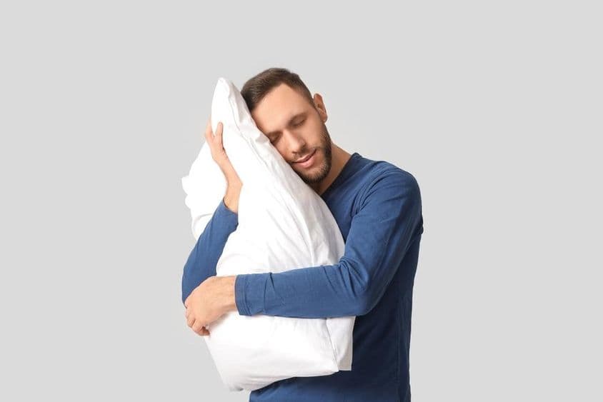 Joven en pijama con almohada suave.