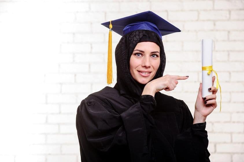 Graduado musulmán feliz posando con diploma en interiores.