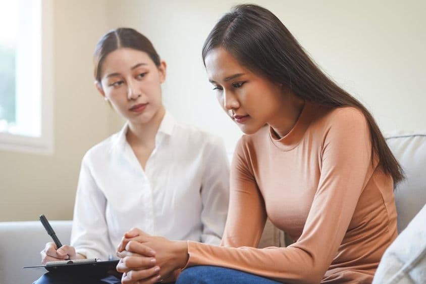 Joven asiática triste consultando con un psicólogo.
