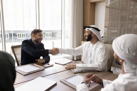 Socios comerciales multinacionales concluyendo una negociación exitosa con un apretón de manos.