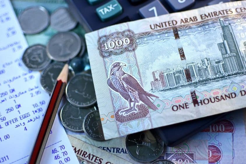 Billete de 1000 dirham de EAU y un puñado de monedas.