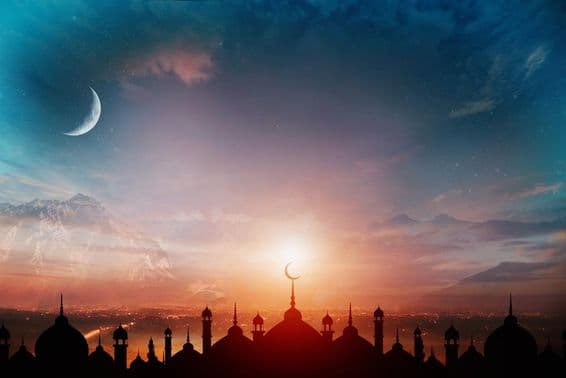 Cúpulas de mezquita contra un cielo azul crepuscular con una luna creciente al fondo.