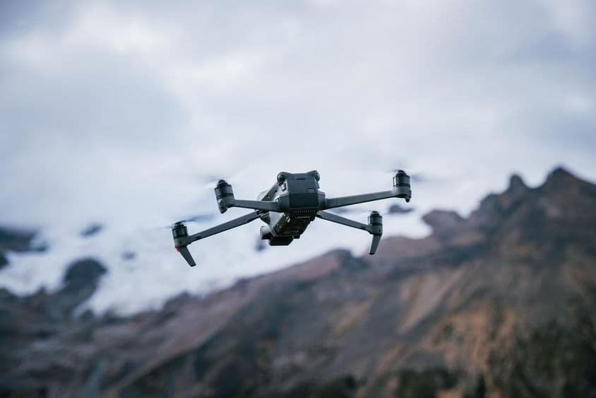 Drone volando sobre la cima de una montaña a gran altitud.