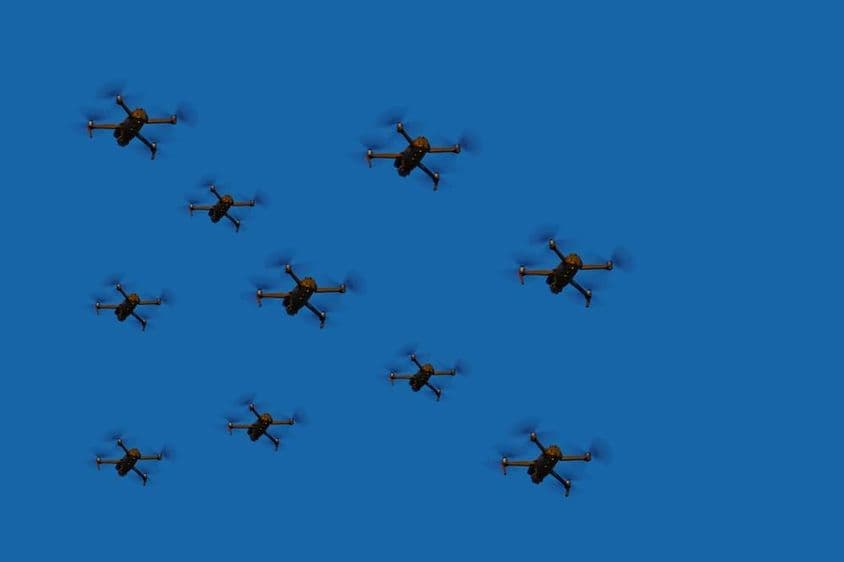 Drones volando en formación contra un cielo azul.