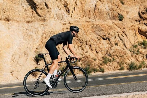 Ciclista con ropa deportiva negra en intenso entrenamiento al aire libre.
